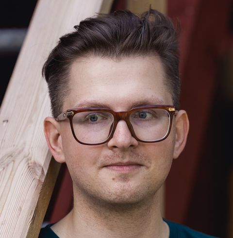 Photo of Jürgen Šuvalov. I have short brown hair that is combed back and slightly messy. I am wearing glasses with a thick brown frame. Slightly smiling and looking to the left. 